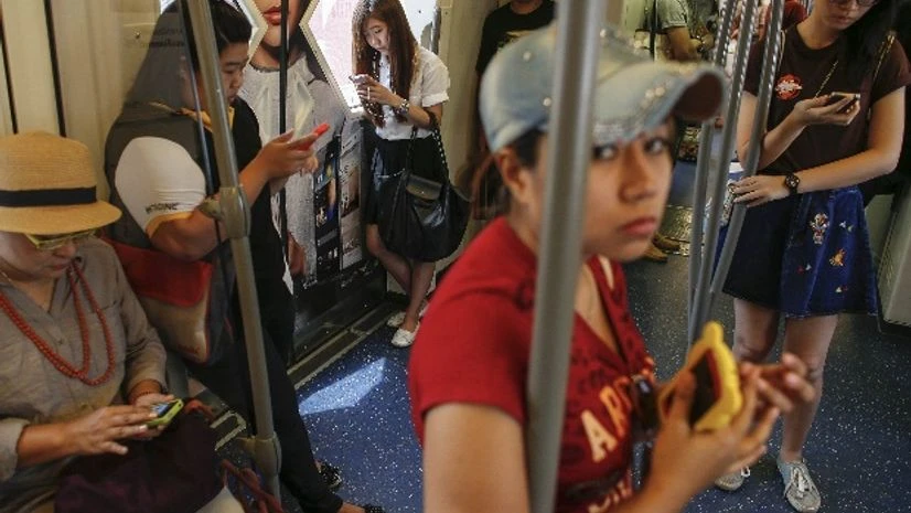 Passengers use their mobile phones on a skytrain in Bangkok Passengers use their mobile phones on a skytrain in Bangkok