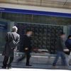 A man (L) looks at a stock quotation board outside a brokerage in Tokyo
