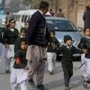 A plainclothes security officer escorts students rescued from nearby school during a Taliban attack in Peshawar, Pakistan