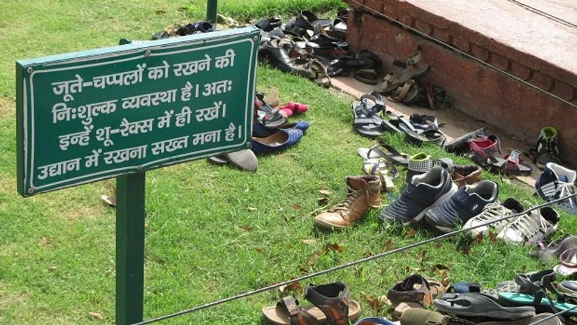 Shoes strewn on the lawns of the Taj Mahal next to a sign forbidding it