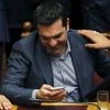 Greek Prime Minister Alexis Tsipras checks a mobile phone during a voting session at the Parliament in Athens, Greece
