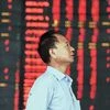 An investor stands at a brokerage house, near an electronic board filled with red figures indicating rising prices, in Fuyang, China on Tuesday