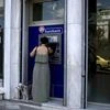 A woman uses a Eurobank ATM in Athens, Greece