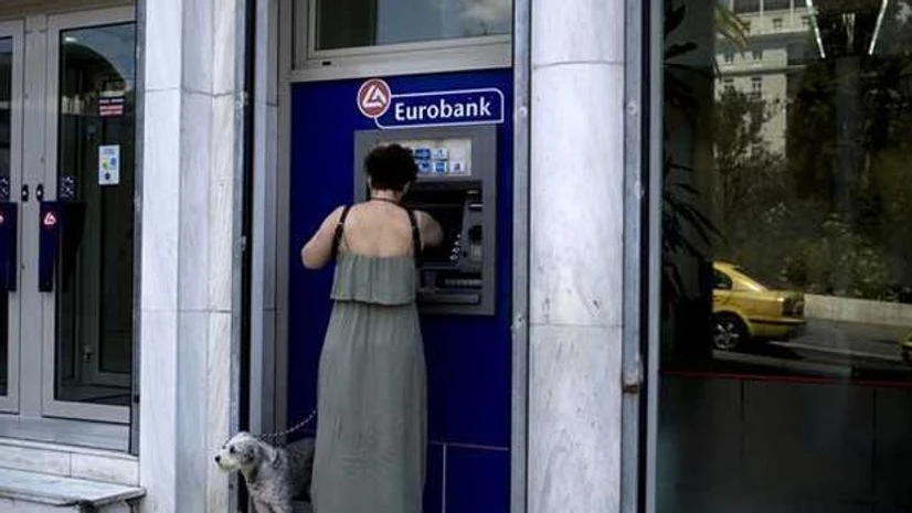A woman uses a Eurobank ATM in Athens, Greece A woman uses a Eurobank ATM in Athens, Greece