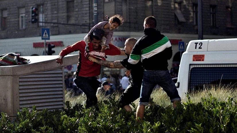 SyriaRefugeeCrisis A Syrian man carrying a child (left) scuffles with a Hungarian nationalist in front of the Keleti train station in Budapest, Serbia on Friday (September 4, 2015). Minor skirmishes broke out at the Keleti train station, where hundreds of migrants and