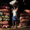 A labourer carries a sack of onions at a vegetable market in Kolkata