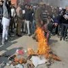 Sikh protesters trampling the burning effigy of Parkash Singh Badal-led government, as a police officer tries to stop them during their protest against the alleged desecration of religious book and Punjab firing incident, at Lal Chowk in Srinagar.