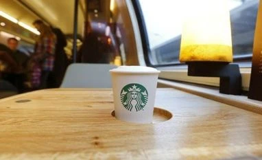 Starbucks ties up with Alibaba to expand coffee biz, revive sales in China The company's logo is printed on a cup of coffee standing on a table in a new Starbucks store on a train of Swiss rail operator SBB in Zurich
