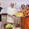 Prime Minister Narendra Modi presenting Gold bond to a woman during the launch of Government Gold schemes, in New Delhi on Thursday. Union Finance Minister Arun Jaitley, Minister of State for Finance, Jayant Sinha and the Minister of State for Commer