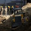 Workers walk past a road construction site in Beijing