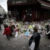 People lay flowers and candles in front of  the restaurant Le Carillon, one of the establishments targeted in Friday's gun and bomb attacks, in Paris