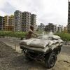 A labourer loads cement bags onto an improvised motorized rickshaw at the construction site of a residential complex on the outskirts of Kolkata