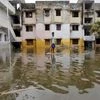 A man uses a board to float through a flooded street to reach to a market place in Chennai