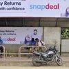 Commuters sit at a bus stop adorned with an advertisement of Indian online marketplace Snapdeal featuring Bollywood actor Aamir Khan, in Bengaluru