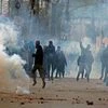 Angry youth throwing stones on police amid tear gas smoke fired by police to disperse them during clashes on Srinagar-International Airport Road at Peerbagh in Srinagar.