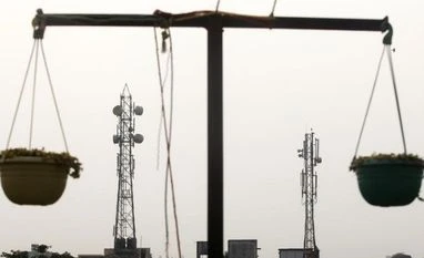 Trai suggests base price of Rs 11k cr for 700-MHz band Telecommunication towers are pictured through hanging flower pots at a residential building in Kolkata (Photo: Reuters)