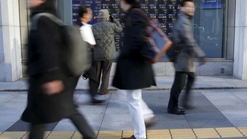A man looks at an electronic stock quotation board as passers-by walk past, outside a brokerage in Tokyo A man looks at an electronic stock quotation board as passers-by walk past, outside a brokerage in Tokyo