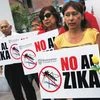 People hold signs against the Zika virus during a fumigation of the cemetery of Surco to prevent the virus and other mosquito-borne diseases in Lima, Peru