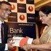 Founder, MD and CEO, Bandhan Bank, Chandra Shekhar Ghosh  hands over the first card to a customer during the launch of the bank's International Debit Card and NRI Banking in Kolkata