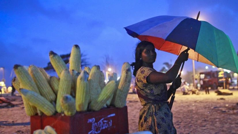 A woman selling grilled corn takes shelter under an umbrella as it rains on a beach in Mumbai. Photo: Reuters A woman selling grilled corn takes shelter under an umbrella as it rains on a beach in Mumbai. Photo: Reuters