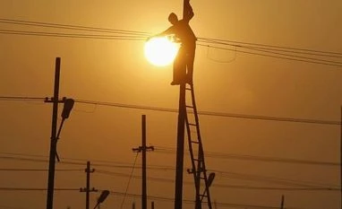 Tata Power's network roll-out plan options being assessed by regulators A worker is silhouetted against the setting sun while installing an overhead electric cable pole on the banks of river Ganges, Allahabad
