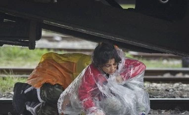 Slovenia, Croatia ban refugee transit to other European countries Migrant children cross railway tracks under a freight train during rainfall at the northern Greek border station of Idomeni