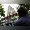 A man looks at a screen across a road displaying the Sensex on the facade of the Bombay Stock Exchange (BSE) building in Mumbai