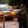 A policeman keep watch as a Japanese convoy drives, as relatives of victims of an attack on the Holey Artisan Bakery and the O'Kitchen Restaurant, visited the site, in Dhaka