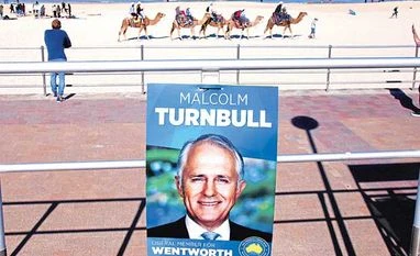Australian PM inches closer to winning majority govt Tourists ride camels along Bondi Beach near a poster promoting the Australian Prime Minister Malcolm Turnbull in front of a voting station, located in the Bondi Surf Lifesavning Club, in Sydney, Australia