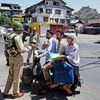 A CRPF jawan verifies the identy of a family riding a scooter during curfew in Srinagar