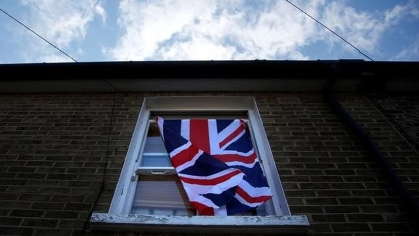 A British flag flutters in front of a window in London A British flag flutters in front of a window in London