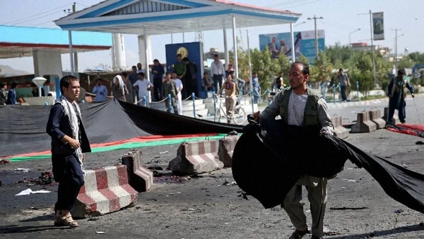 An Afghan man uses a banner in the colors of the Afghan flag to cover victim's blood, after a deadly explosion struck a protest march by ethnic Hazaras, in Kabul An Afghan man uses a banner in the colors of the Afghan flag to cover victim's blood, after a deadly explosion struck a protest march by ethnic Hazaras, in Kabul