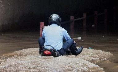 A man rides his bike through a waterlogged road after heavy downpour A man rides his bike through a waterlogged road after heavy downpour