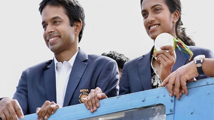 Olympic Silver Medalist P V Sindhu with her Coach Pullela Gopichand flaunts her medal after her arrival at Rajiv Gandhi International Airport in Hyderabad. Olympic Silver Medalist P V Sindhu with her Coach Pullela Gopichand flaunts her medal after her arrival at Rajiv Gandhi International Airport in Hyderabad.