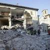Firefighters stand in front of a collapsed house in Amatrice, central Italy