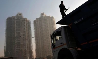 Mandatory AC cabins in trucks: Automakers ask govt to put decision on hold A labourer stands on a truck carrying construction materials at a construction site of residential buildings <b> Reuters <b>