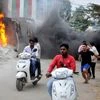 Men make their way past a burning lorry in Bengaluru