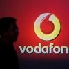 A man casts a silhouette onto an electronic screen displaying a Vodafone logo, in Mumbai. Photo: Reuters