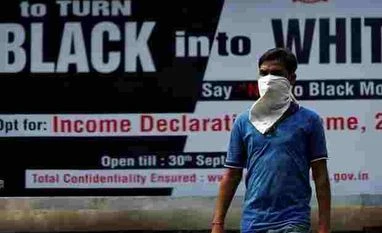 Final black money tally may go up by Rs 10,000 cr A man walks pasts an income tax billboard in New Delhi