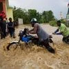 Two men push a motorbike through a street flooded by a nearby river that overflowed from heavy rains caused by Hurricane Matthew, in Leogane, Haiti. Photo: PTI