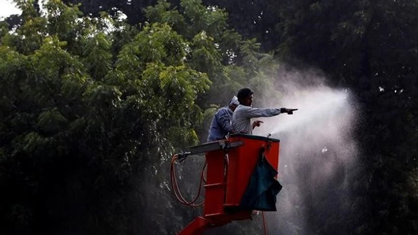 NDMC workers spray water on trees to settle down the dust in New Delhi.Reuters NDMC workers spray water on trees to settle down the dust in New Delhi.Reuters