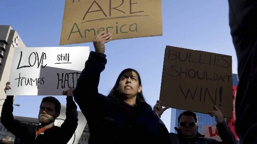 Protesters hold signs as they march in opposition to the election of President-elect Donald Trump immigrants, migrants, Trump, America