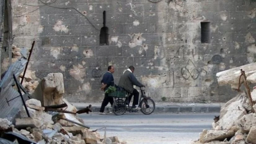 A man walks past a man riding a bicycle near the rubble of damaged buildings in the rebel held area of Old Aleppo A man walks past a man riding a bicycle near the rubble of damaged buildings in the rebel held area of Old Aleppo