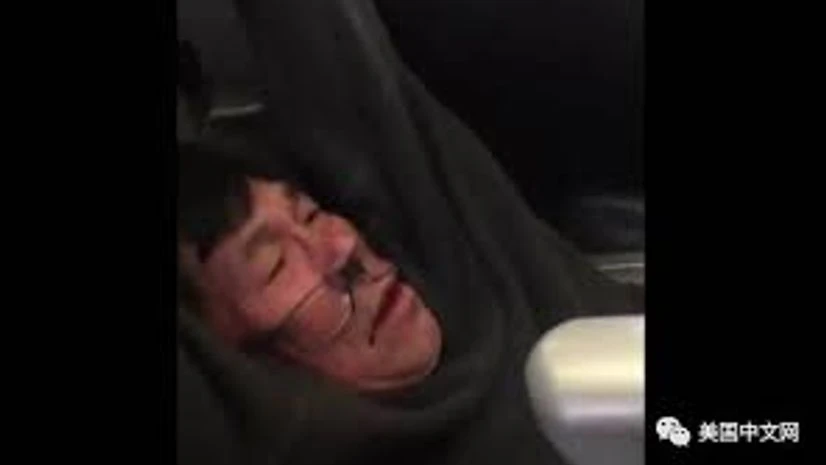 The Asian man was dragged forcibly from his seat on a flight with his glasses askew and his shirt above his abdomen. The Asian man was dragged forcibly from his seat on a flight with his glasses askew and his shirt above his abdomen.