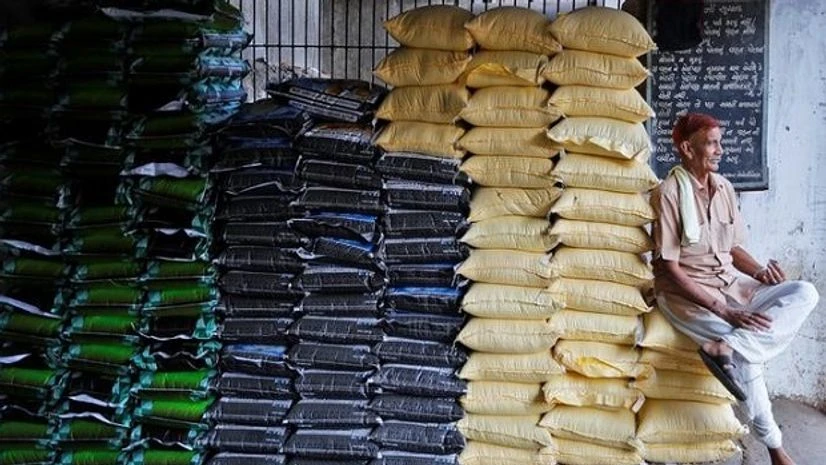 A labourer sits on sacks of food grains while waiting for customers at a wholesale market in Ahmedabad A labourer sits on sacks of food grains while waiting for customers at a wholesale market in Ahmedabad