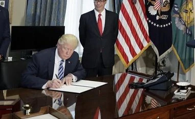 Considerable uncertainty over economic policies of Donald Trump: IMF Donald Trump signs a financial services executive order as Treasury Secretary Steven Mnuchin looks on at the Treasury Department in Washington
