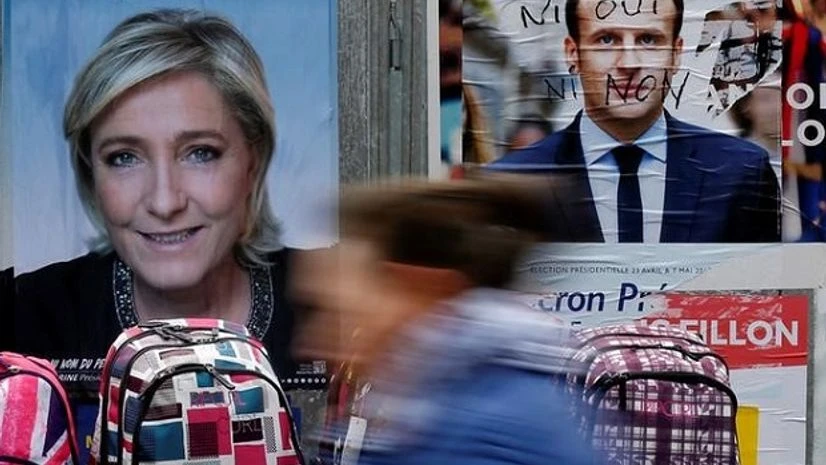 A woman walks past official posters of candidates for the 2017 French presidential election Marine Le Pen and Emmanuel Macron Photo: Reuters French Elections