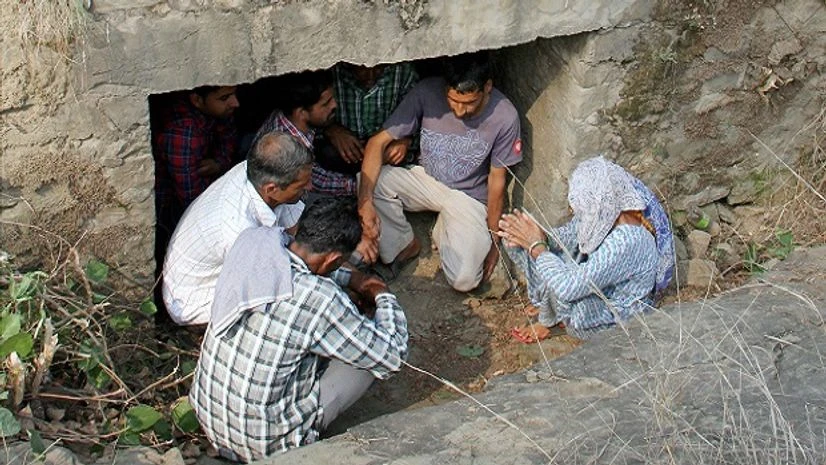 Pakistan Border villagers take shelter under a small bridge on a road after firing from Pakistan at Jhanghar village near the Line of Control (LoC) at Nowshera sector 145km about from Jammu. Photo: PTI