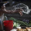 A vendor splashes water as he sells vegetable next to a railway track in Dhaka.(Photo: Reuters)