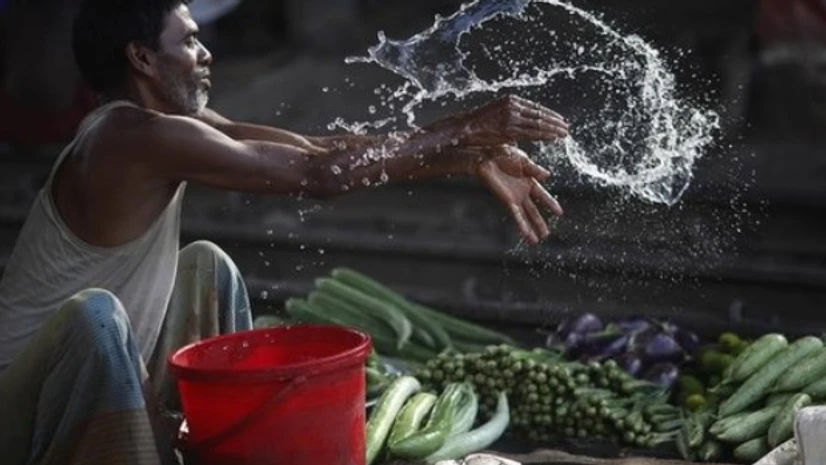 A vendor splashes water as he sells vegetable next to a railway track in Dhaka.(Photo: Reuters) A vendor splashes water as he sells vegetable next to a railway track in Dhaka.(Photo: Reuters)